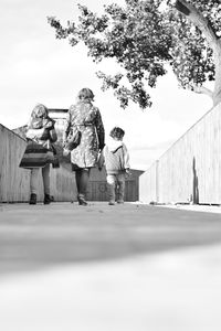 Woman standing on sidewalk against sky