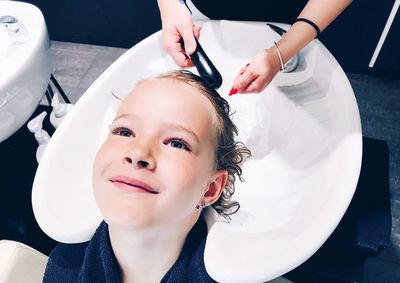 Cropped hairdresser washing hairs of girl in salon