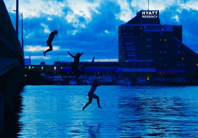 Silhouette man jumping in swimming pool against sky