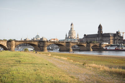 Bridge over river in city against clear sky