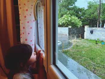 Side view of boy looking through window