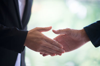 Midsection of businessman and colleague shaking hands at office