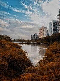 Lake by buildings against sky during autumn