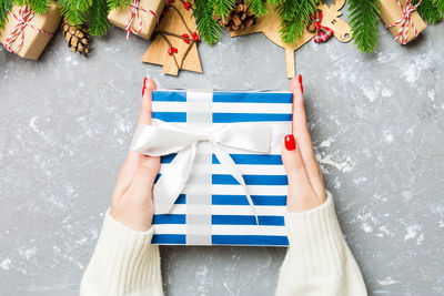 Top view of a woman holding a gift box in her hands. fir tree and christmas decorations. new year.