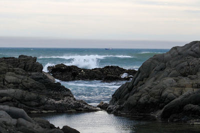 Scenic view of ocean waves breaking against the rocks with rock pools in the front area