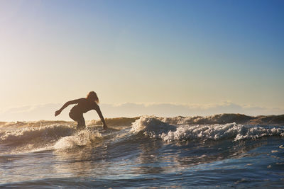 Man surfing in sea against clear sky