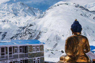 Buddha statue against snowcapped mountain