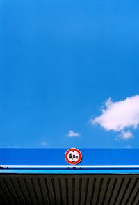 Low angle view of number on gas station against blue sky