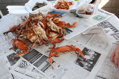 Cropped hand by crabs on table