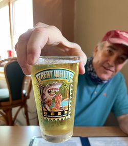 Midsection of man holding drink sitting on table