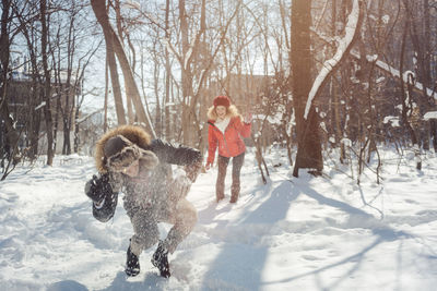 Happy couple playing at snow covered forest during winter