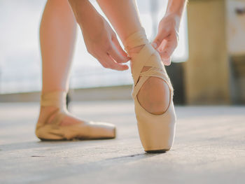 Low section of ballet dancer wearing shoe in studio