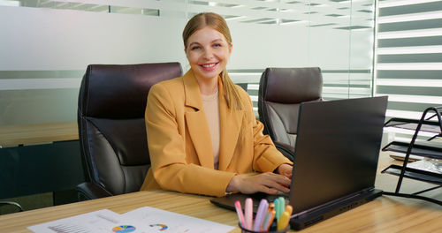Portrait of business woman working on laptop screen in office. 