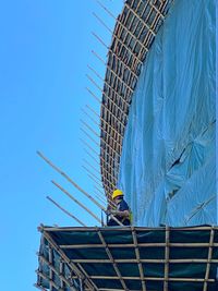 Low angle view of construction site against clear blue sky