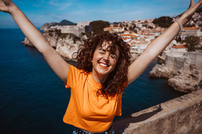 Portrait of young woman standing against sky