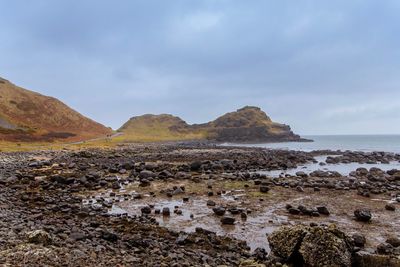 Rocks by sea against sky