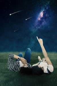 Digital composite image of woman lying on field against sky at night