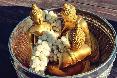 High angle view of buddha statues and floral garland in container