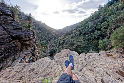 Low section of man on mountain against sky