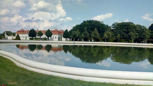 Reflection of trees and houses in lake against sky