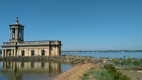 Building by sea against clear blue sky