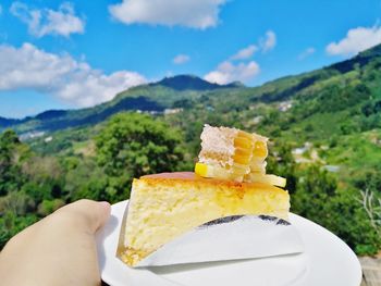 Close-up of hand holding ice cream against mountains