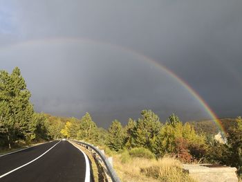 Rainbow over road against sky