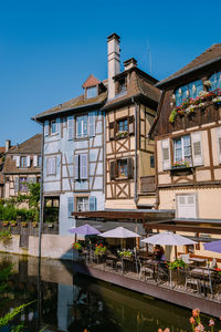 Buildings by lake against blue sky