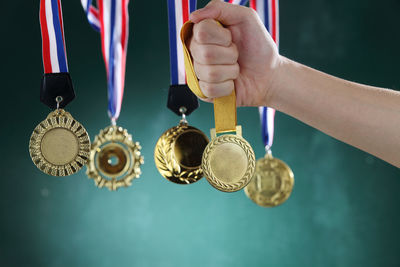 Cropped hand of woman holding medal against wall