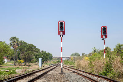 Information sign by railroad tracks against clear sky