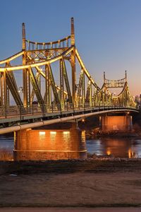 Illuminated bridge over river against sky at night