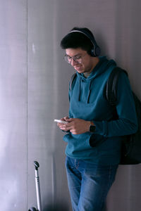 Young man smiles and is typing on his smartphone