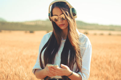 Portrait of young woman wearing sunglasses standing on field