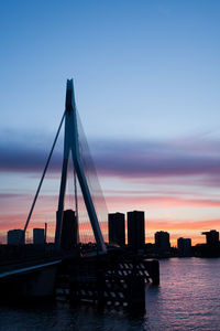 Suspension bridge over sea against sky during sunset