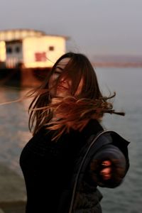 Portrait of woman standing by water against sky