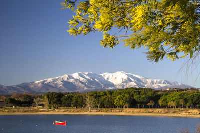 Scenic view of lake and mountains against clear blue sky