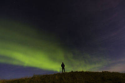 Silhouette man standing on field against aurora borealis at night