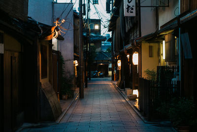 Footpath amidst buildings in city at dusk