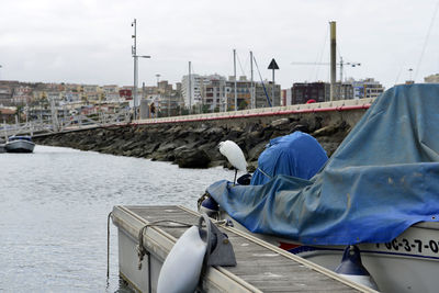 Man lying on boat in city against sky