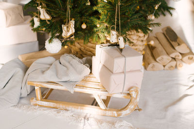 Wooden vintage sleigh with a blanket and gifts under the christmas tree. christmas decor 