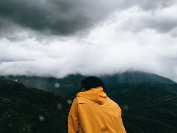 Rear view of person looking at mountains against sky 