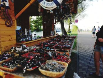 Low section of woman standing by various products for sale at market stall