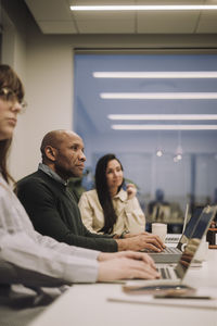 Mature businessman amidst female colleagues planning strategy in meeting at work place