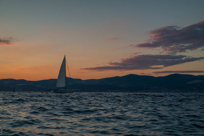 Sailboat sailing on sea against sky during sunset