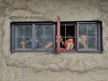 Portrait of boy looking through window in building