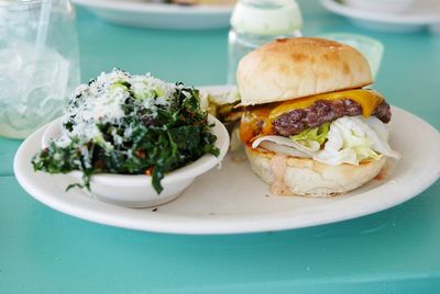 Close-up of cheeseburger and salad on table