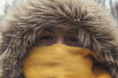 Close-up portrait of young woman hiding in snow