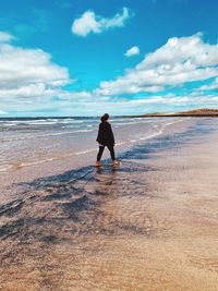 Rear view of man on beach against sky