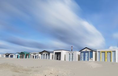 Stilt houses on beach against blue sky