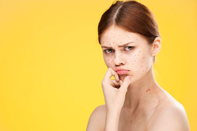 Portrait of young woman against yellow background